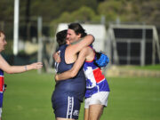 Two footy players hugging on the field.