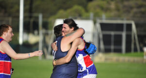 Two footy players hugging on the field.