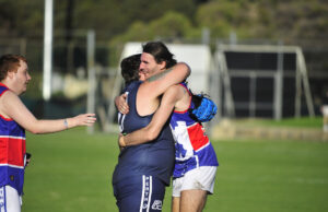 Two footy players hugging on the field.