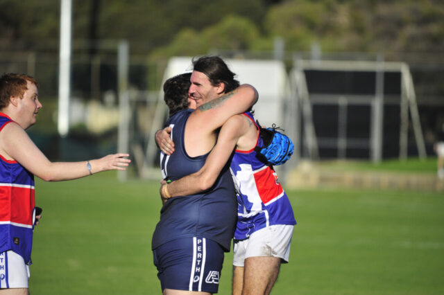 Two footy players hugging on the field.