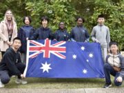 A teacher and seven students pose for photo holding Australian flag.