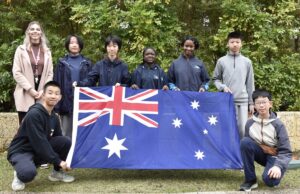 A teacher and seven students pose for photo holding Australian flag.