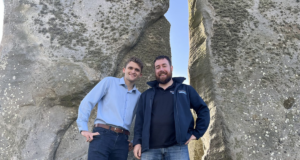 Two men pose for photo at Stonehenge.