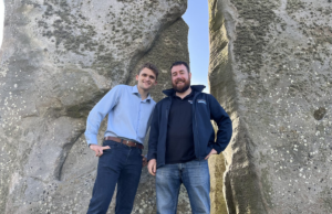 Two men pose for photo at Stonehenge.