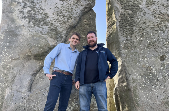 Two men pose for photo at Stonehenge.