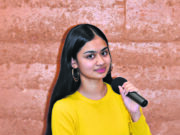 Women in a yellow shirt holding a mic.