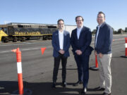 3 men standing in front of a freight train