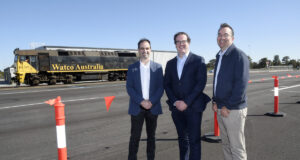 3 men standing in front of a freight train