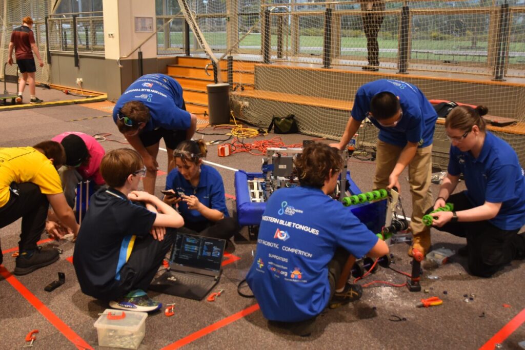 Students on ground fixing robots.