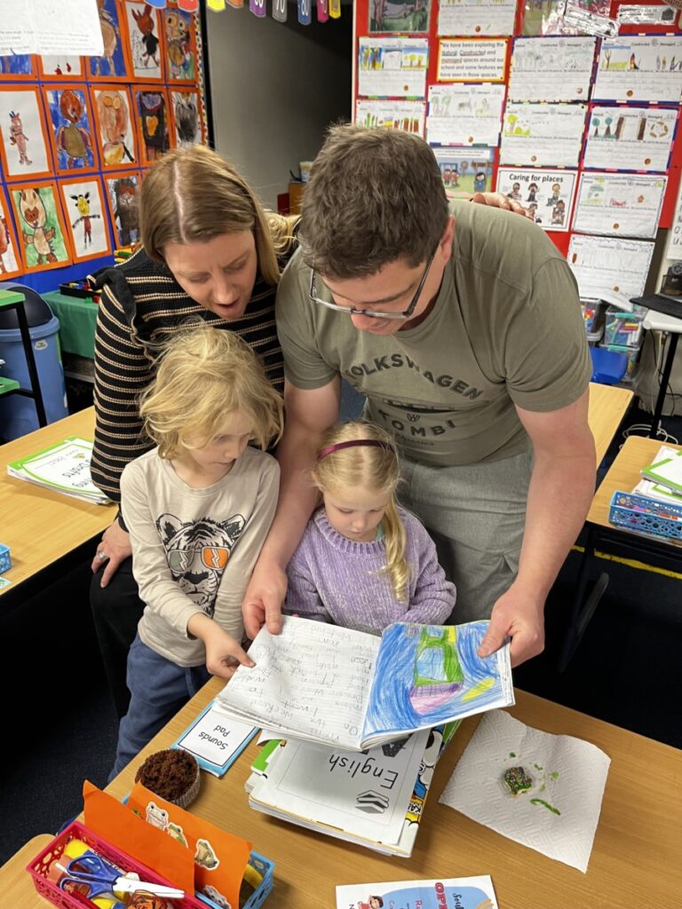 Family reading a book in a classroom. 